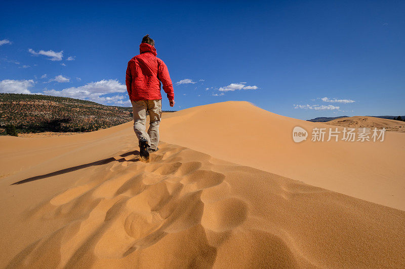 在红色沙丘上徒步旅行的人