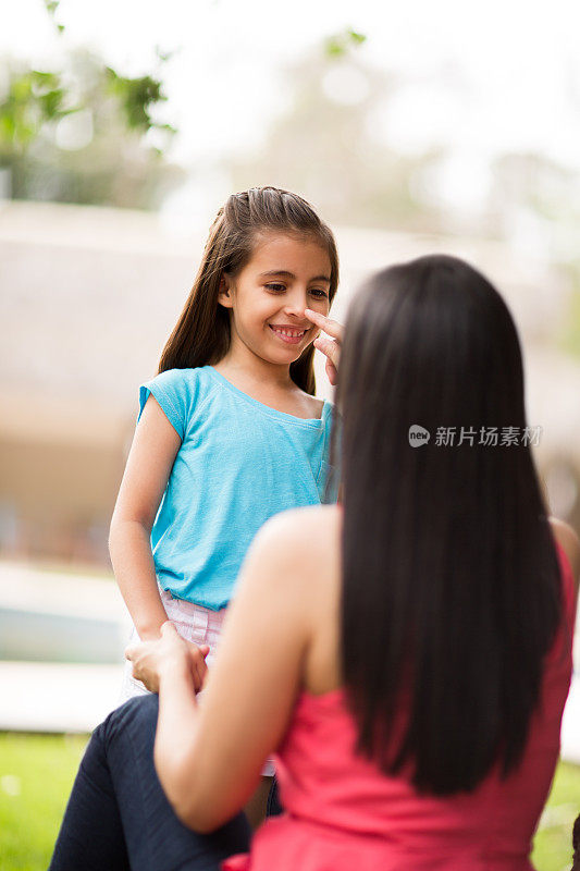 顽皮的拉丁母亲抚摸着小女儿的鼻子