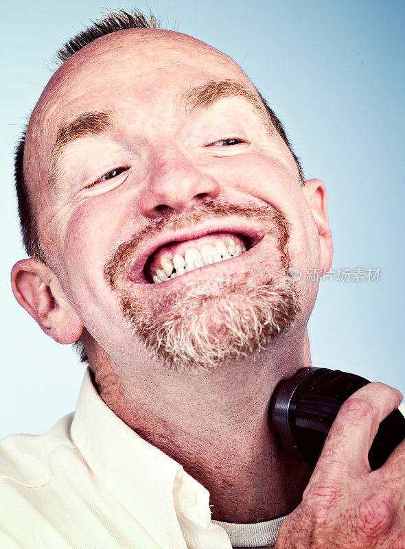 一个成熟的大胡子男人刮着他的脖子，露出一个紧咬着牙齿的微笑