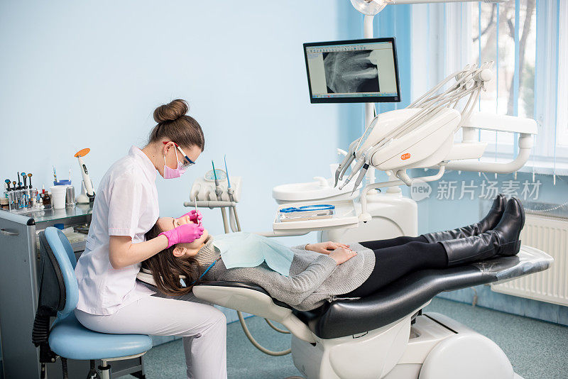女牙医用牙科工具-镜子和探针在牙科诊所治疗病人的牙齿。医学、牙科和保健概念。牙科设备