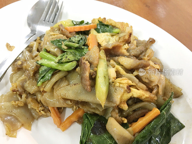 木桌上白底豆沙炒面和猪肉。泰国风格的食物。