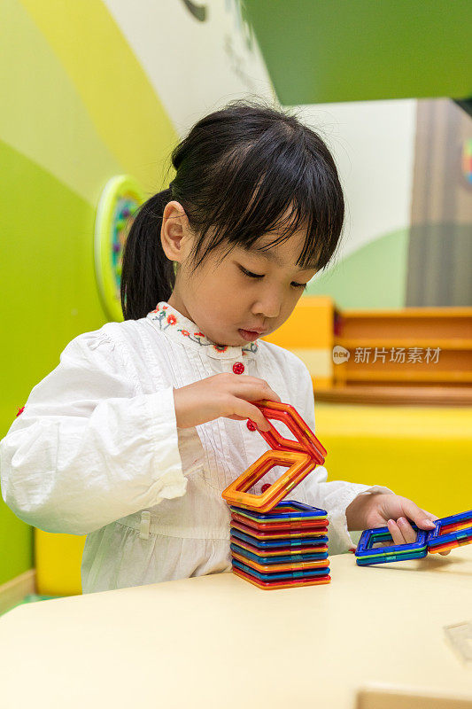 亚洲华人小女孩玩彩色磁铁塑料积木套件