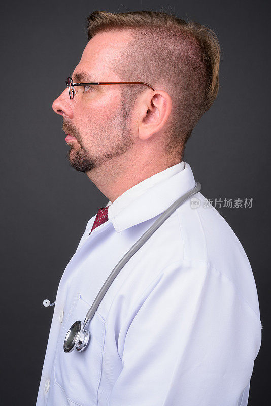 留着金色山羊胡的医生戴着眼镜，衬托着灰色的背景