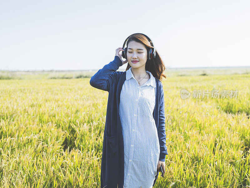 年轻女孩戴着耳机在野外