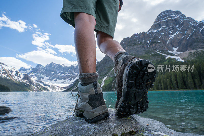 徒步旅行者到达山上的湖，靴子靠近