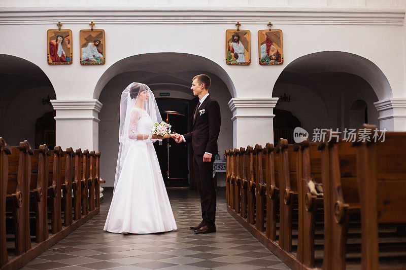 新郎和新娘在教堂里穿着白色的礼服。婚礼仪式。幸福的家庭