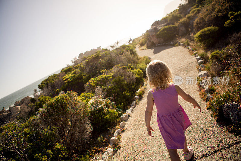 小女孩在海边的一条小路上奔跑
