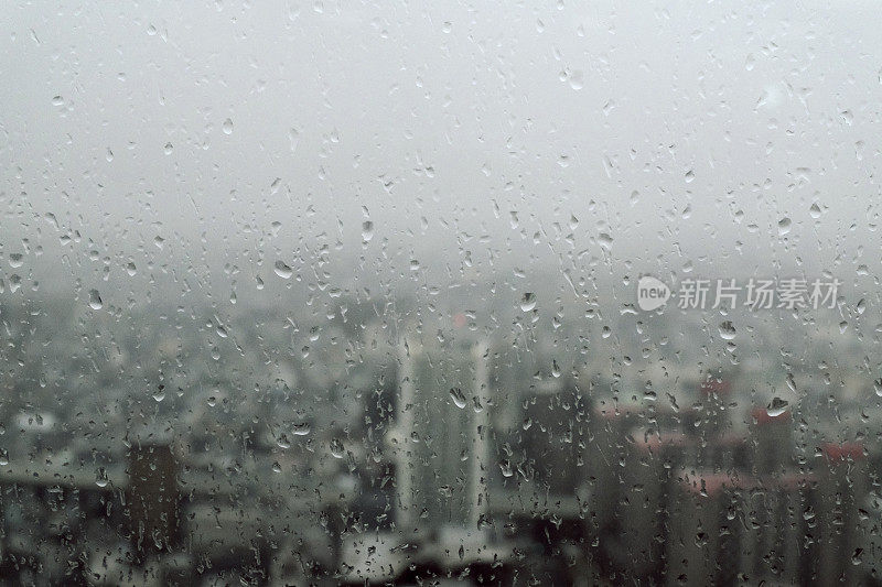 透过玻璃窗外的城市景观与雨滴在摩天大楼