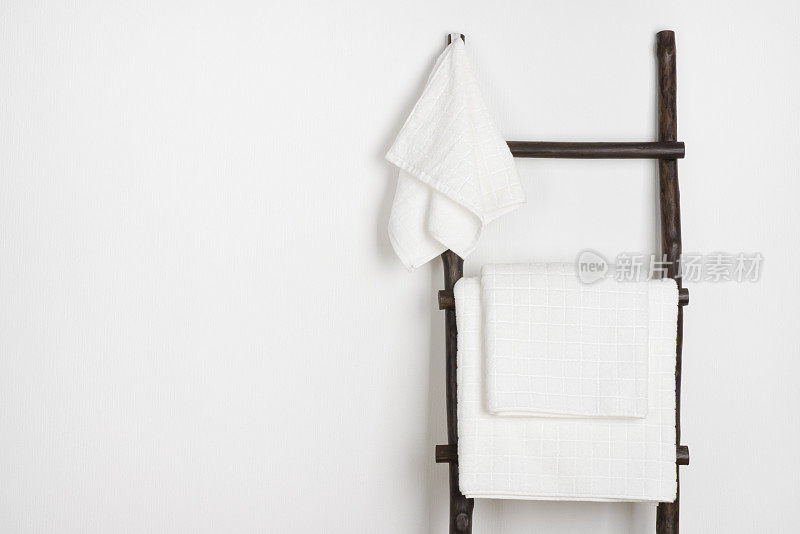 水疗浴巾挂在老式的木制梯上，孤立在白色上