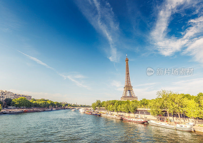 法国巴黎的埃菲尔铁塔，一个阳光明媚的日子，塞纳河和戏剧性的云。