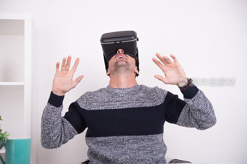 戴着虚拟现实头盔的人，抬起头，双手举在空中