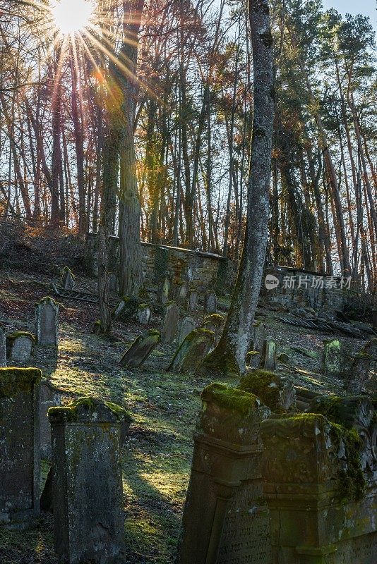 阳光照射在古老的犹太墓地和风化的墓碑上，德国