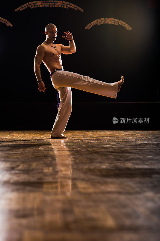 运动员运动腿踢在卡波耶拉训练在一个健康俱乐部。