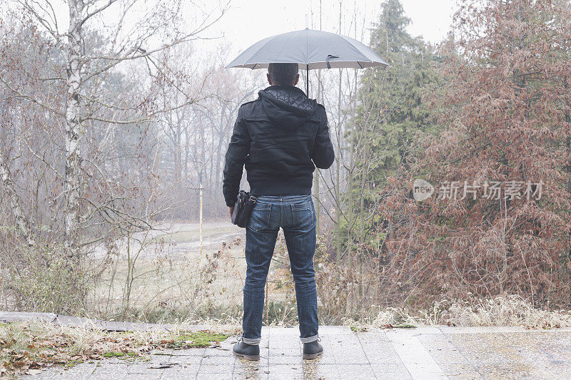 英俊的成年男子在雨天的秋天户外