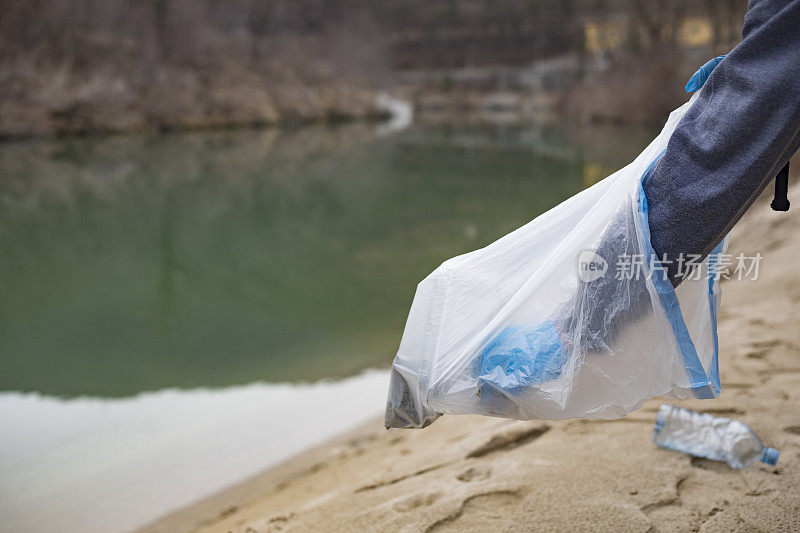 一名年轻人在河边捡塑料瓶