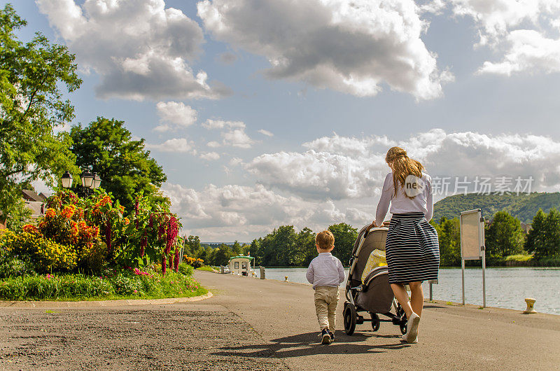 年轻的女人和男孩沿着法国的马斯河散步