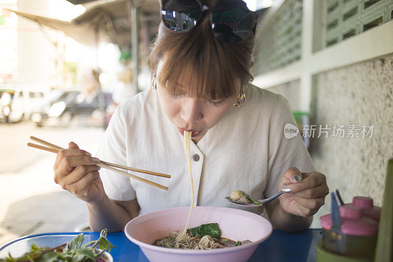 年轻美丽的亚洲女人吃街头小吃