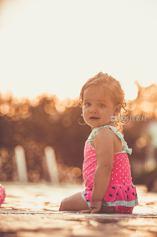 可爱的小女孩在泳池边欣赏夕阳