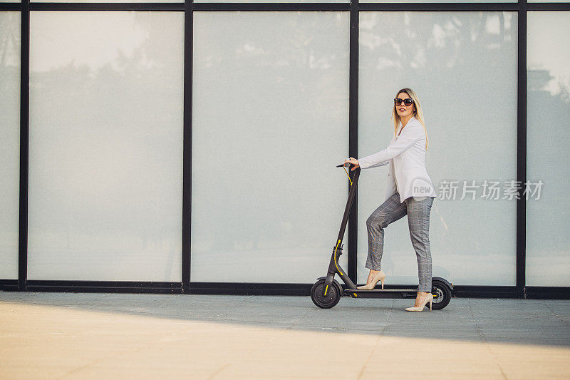 一个女商人骑着滑板车去上班