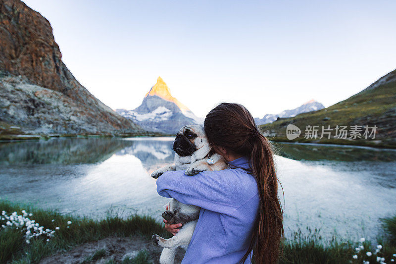 女人和狗遇到明亮的日出在美丽的山湖和马特洪峰在瑞士阿尔卑斯山