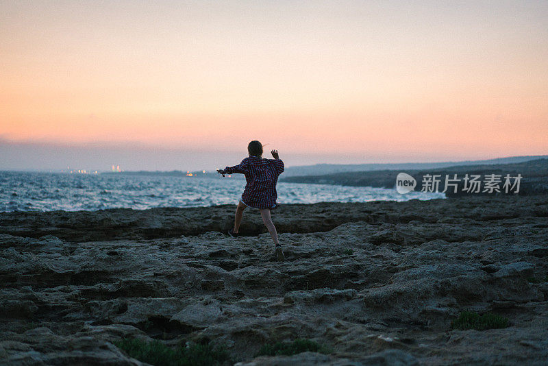 女孩跑在海边附近的海边在日落塞浦路斯