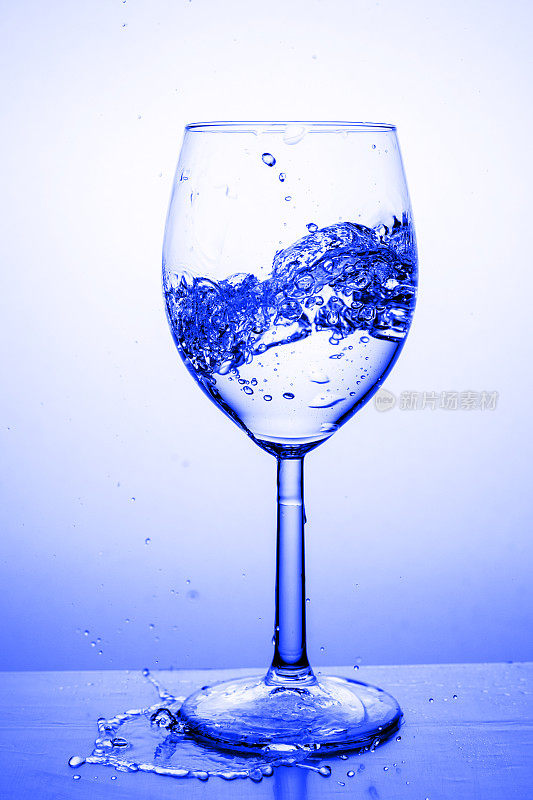 玻璃杯里盛满水，溅起。