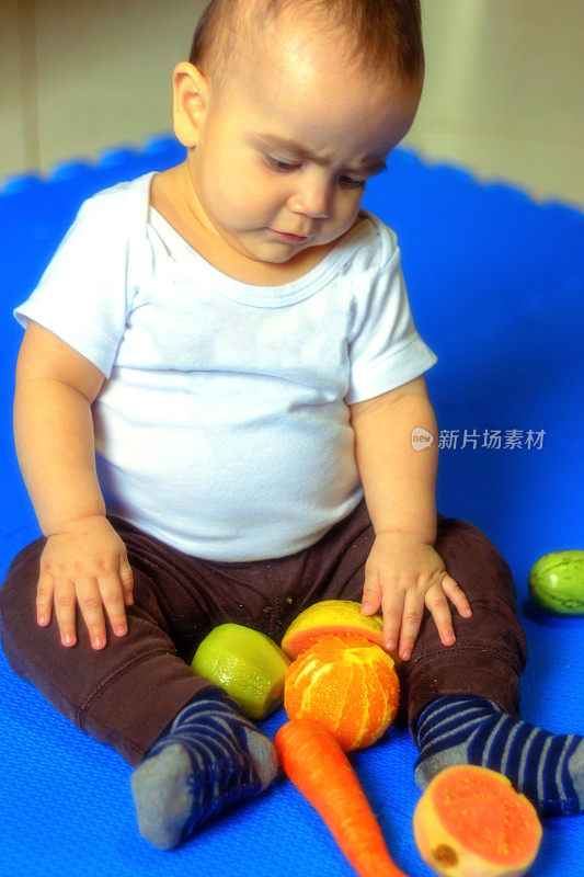 漂亮的宝宝在水果和蔬菜上玩耍。