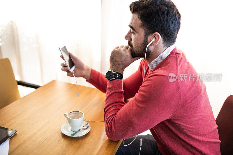 男人坐在café喝咖啡和使用手机