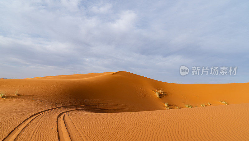 摩洛哥Merzouga沙漠的橙色沙丘和多云的天空。