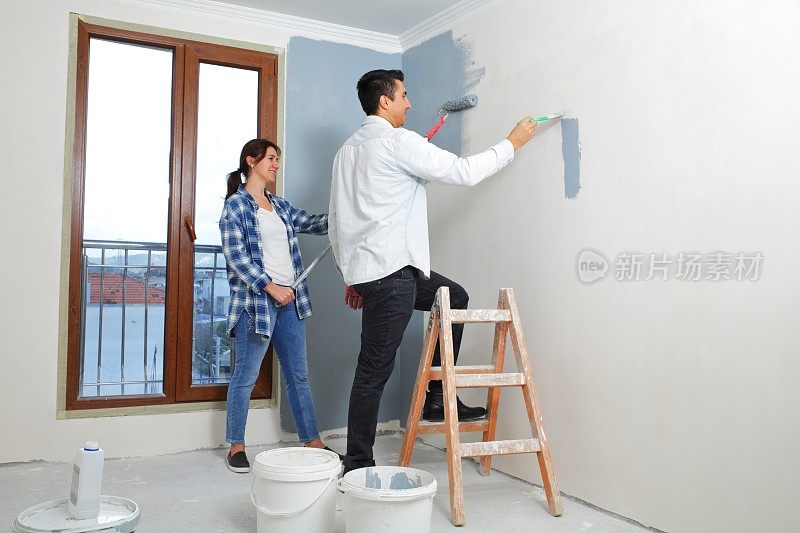 一对年轻夫妇正在粉刷他们新公寓的内墙