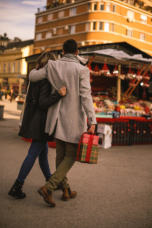 一对异性情侣走在圣诞市场旁边