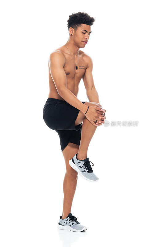 非裔美籍年轻男性穿着短裤在白色背景前伸展