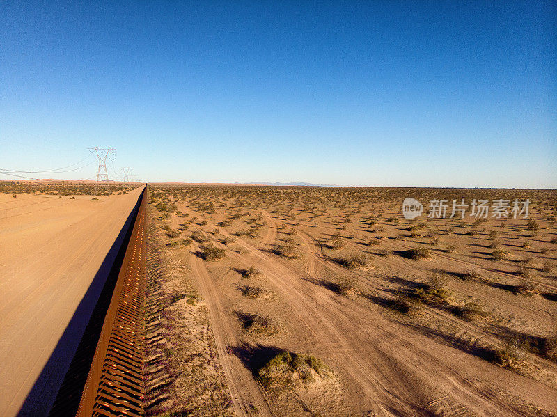 分隔亚利桑那州和加利福尼亚州与墨西哥的国际边境墙的日落无人机图