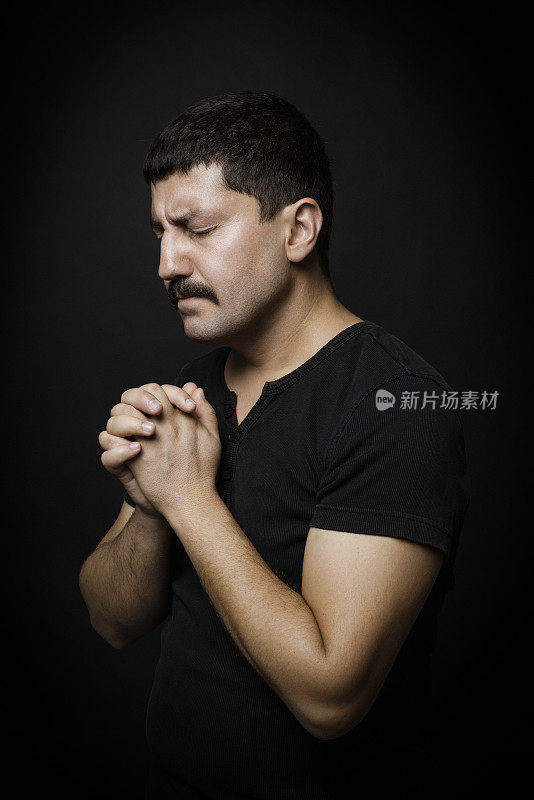祈祷的男人肖像在黑色的背景