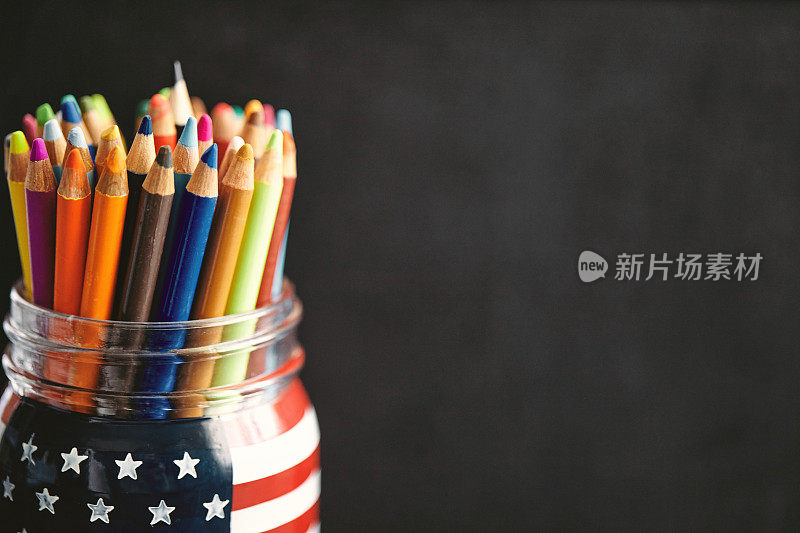 收集的彩色铅笔在磨损的黑板背景爱国美国国旗罐