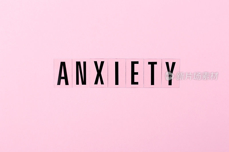 粉红色背景上的字母焦虑。负面情绪的概念。