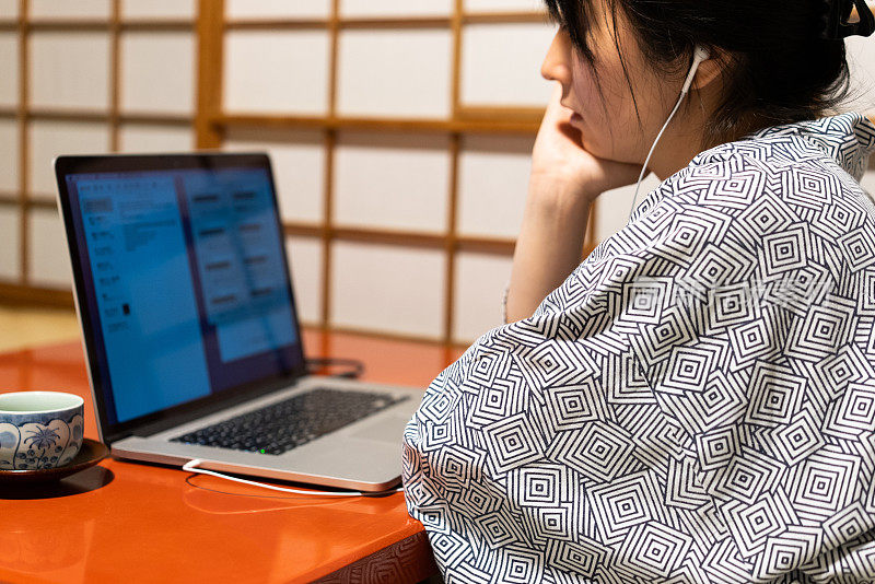 一个正在日本风格的旅馆里使用电脑的女人。