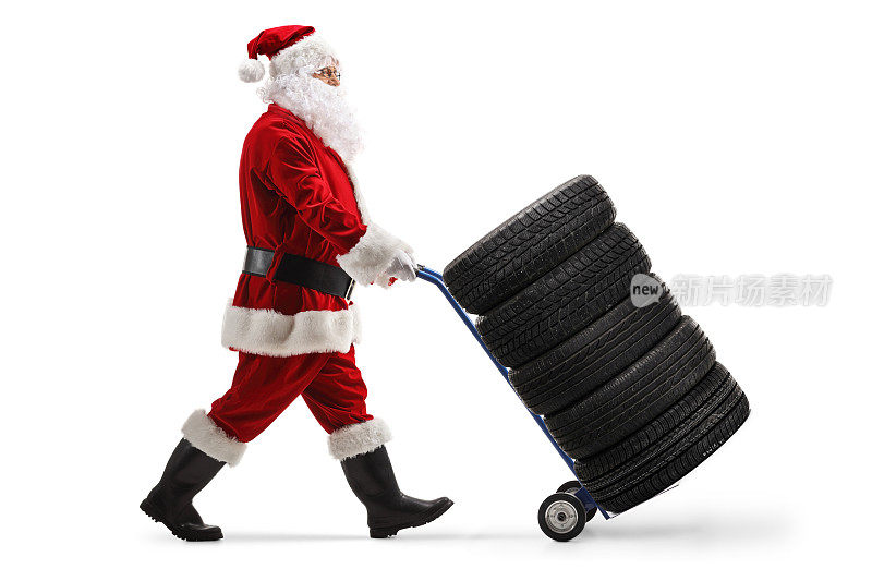 一个圣诞老人推着汽车轮胎在手推车上的全长侧面照片