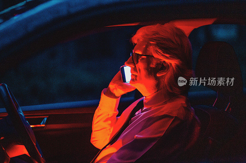 神秘男子在发光的汽车内部使用智能手机