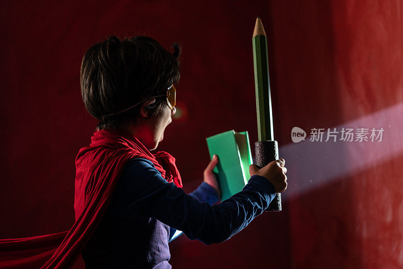 小学生穿着超级英雄服装拿着书和笔的照片