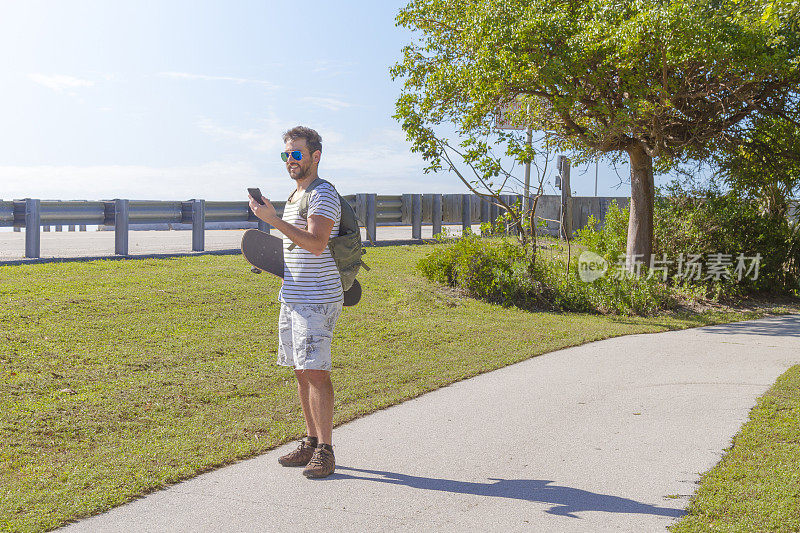美国佛罗里达州基韦斯特，一个炎热的夏日，一名年轻人正在用智能手机发短信