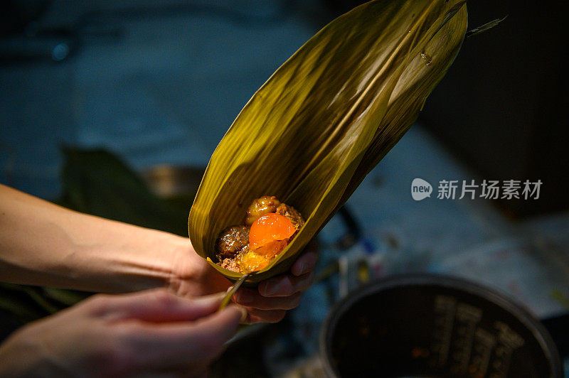 女人用手包粽子。端午节的传统食品