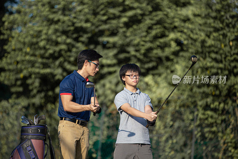 亚洲华人父亲在高尔夫球场指导十几岁的儿子高尔夫课