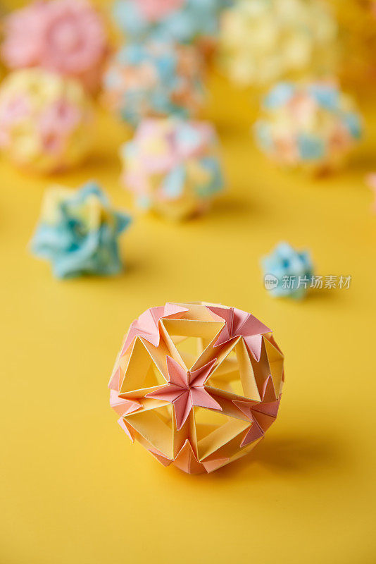 Set的multicolorÂ手工制作modularÂ折纸球或Kusudama孤立在黄色背景。视觉艺术，几何学，折纸艺术，纸工艺品。特写，选择性聚焦，复制空间。