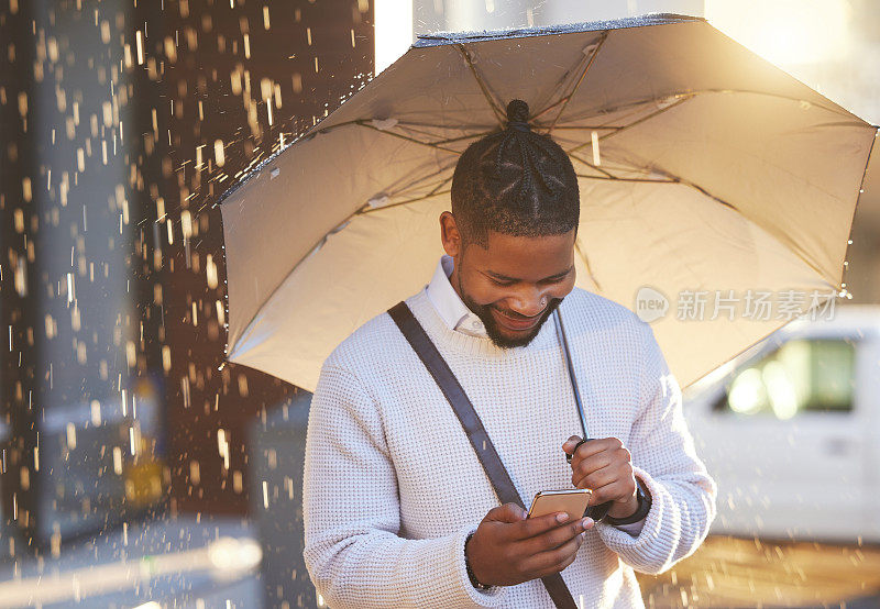 在城市里，一个下雨天，一个年轻的商人打着伞打着手机