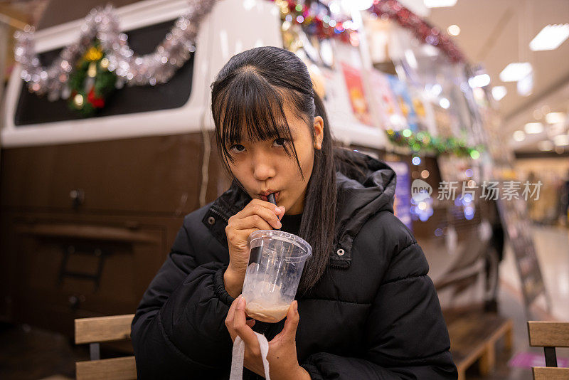 十几岁的女孩在美食广场喝一杯冷饮