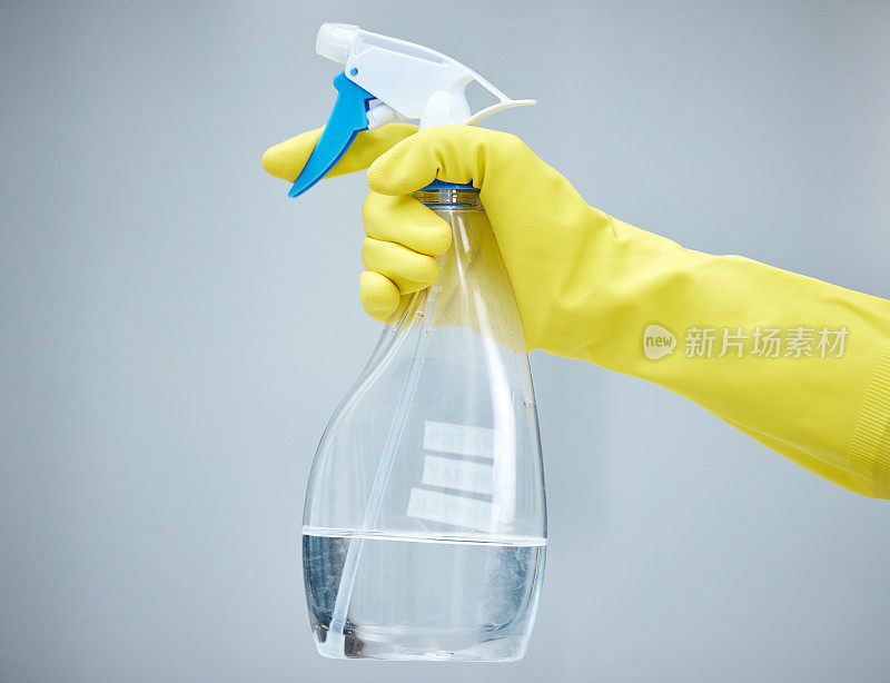 照片中一只手拿着喷雾瓶，戴着黄色手套