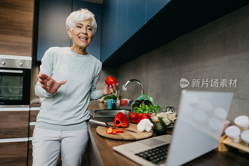 一位女士在厨房里用笔记本电脑打电话