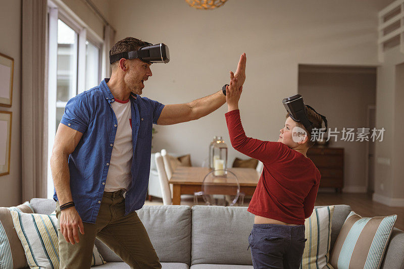戴着虚拟现实头盔的白种父子在家中互相击掌