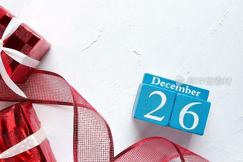 12月26日，木制日历显示日期12月26日和红色礼盒在桌子上。